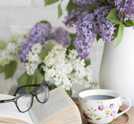 Blumen, ein Buch, eine Brille und eine Tasse Kaffee