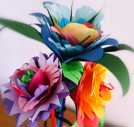 Das Bild zeigt drei bunte Papierblumen, selbst gebastelt