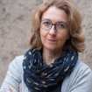 Porträtfoto Elisa Jakob, eine mittelalte Frau mit wallenden blonden Haaren, die ernst in die Kamera schaut