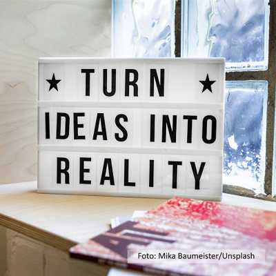 Wechselbuchstabentafel mit dem englischen Schriftzug Turn Ideas into Reality (auf Deutsch: Ideen in die Realität umsetzen)