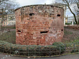 Eine rundförmige historische Wehranlage mit Schießscharten steht in einem Park.