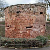 Eine rundförmige historische Wehranlage mit Schießscharten steht in einem Park.
